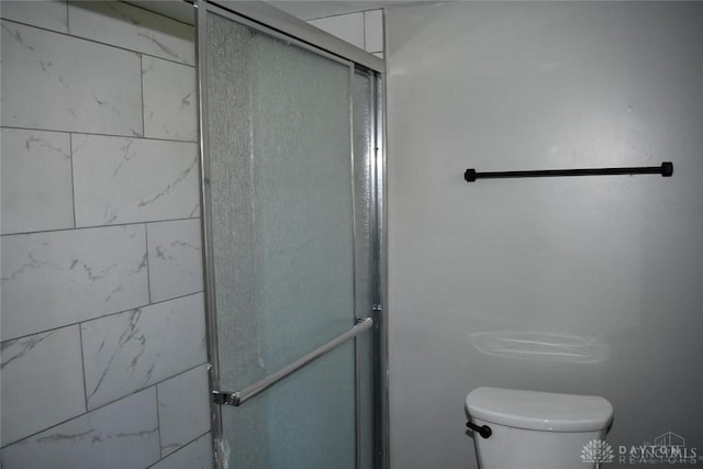 bathroom featuring a shower with shower door and toilet