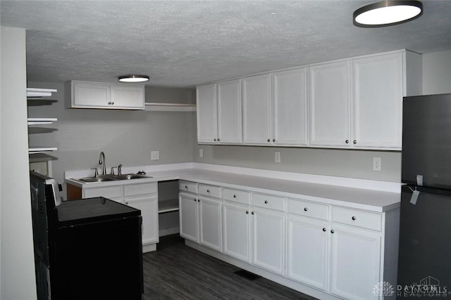 kitchen with white cabinets, black refrigerator, sink, dark hardwood / wood-style flooring, and range