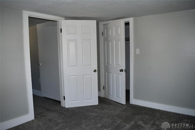 unfurnished bedroom with dark colored carpet and a textured ceiling