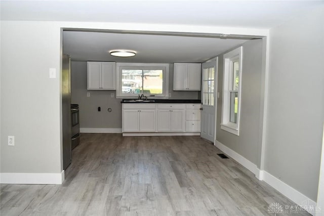 kitchen with white cabinets, range, light hardwood / wood-style floors, and sink