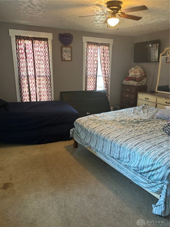 bedroom with ceiling fan, carpet flooring, and a textured ceiling