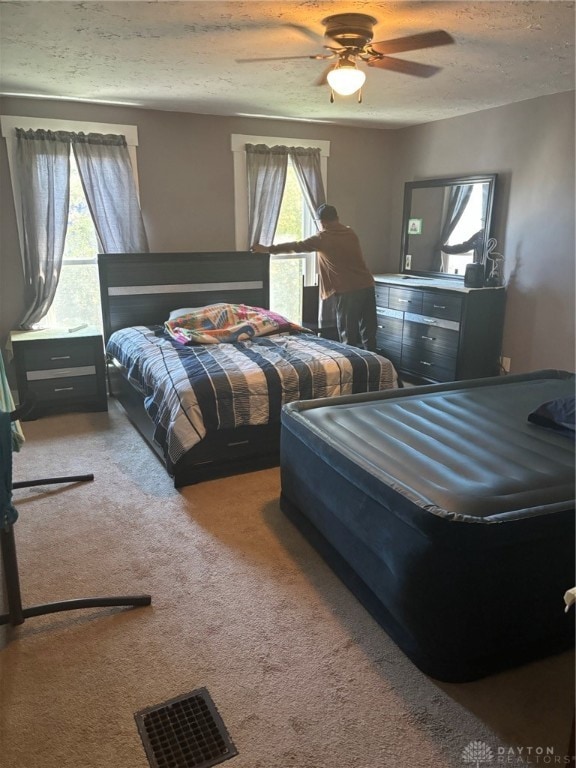 bedroom featuring ceiling fan, a textured ceiling, and carpet floors