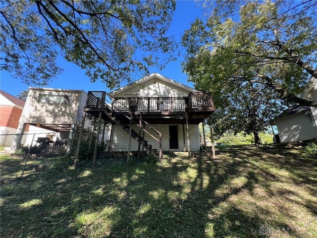 rear view of property featuring a wooden deck and a lawn