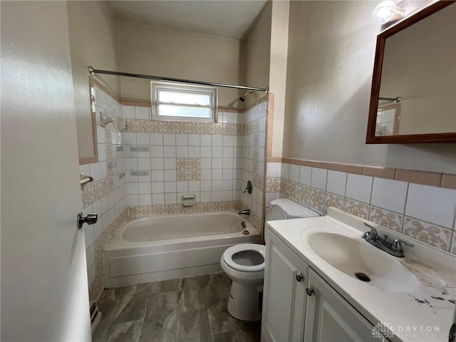 full bathroom with toilet, tiled shower / bath, vanity, and tile walls