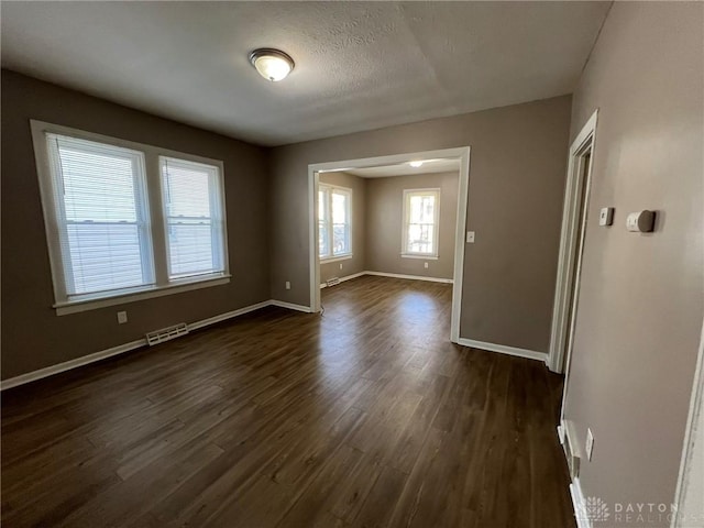 empty room featuring a textured ceiling and dark hardwood / wood-style flooring