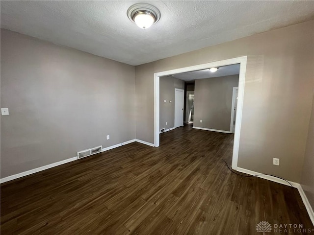 unfurnished room with a textured ceiling and dark hardwood / wood-style flooring