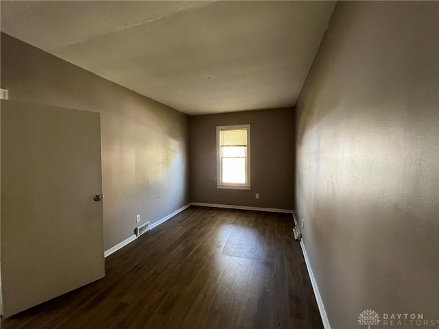 empty room with dark hardwood / wood-style flooring