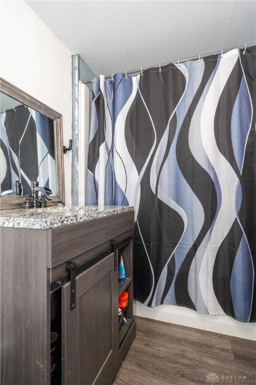 interior space featuring a shower with curtain, vanity, and wood finished floors