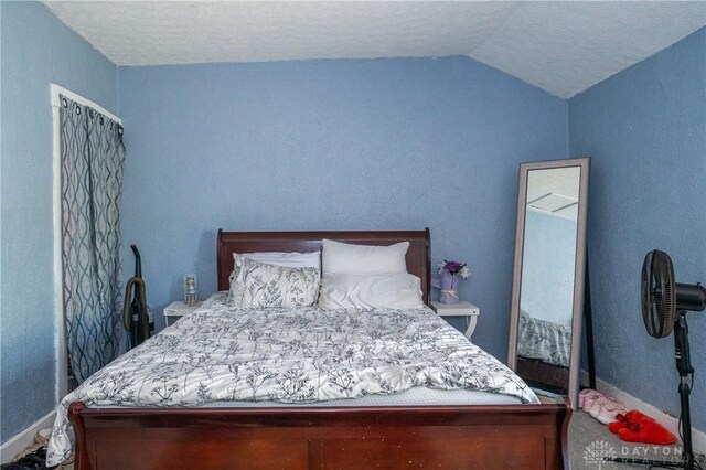 bedroom with a textured ceiling and lofted ceiling