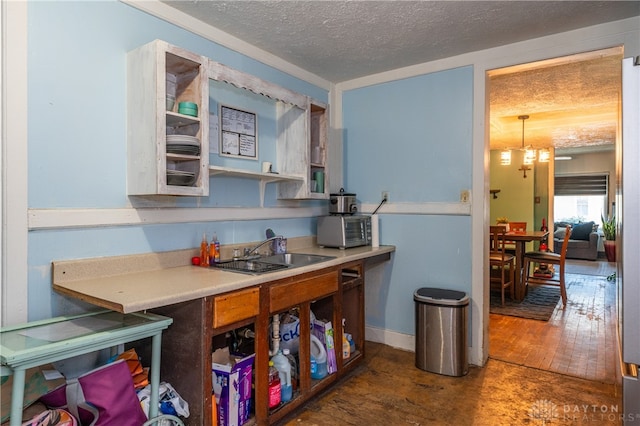 kitchen featuring dark hardwood / wood-style flooring, a textured ceiling, a notable chandelier, and sink