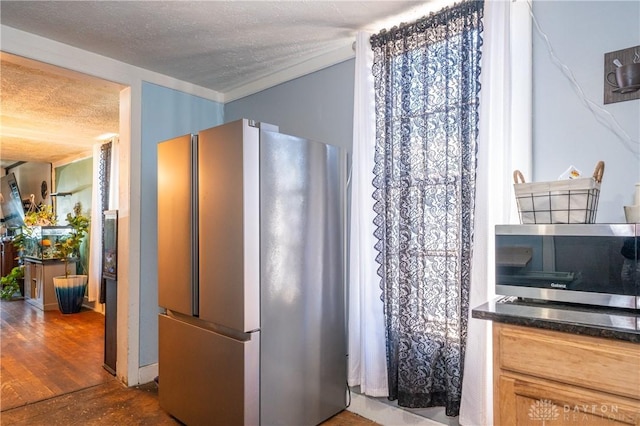 kitchen featuring wood finished floors, a textured ceiling, and freestanding refrigerator