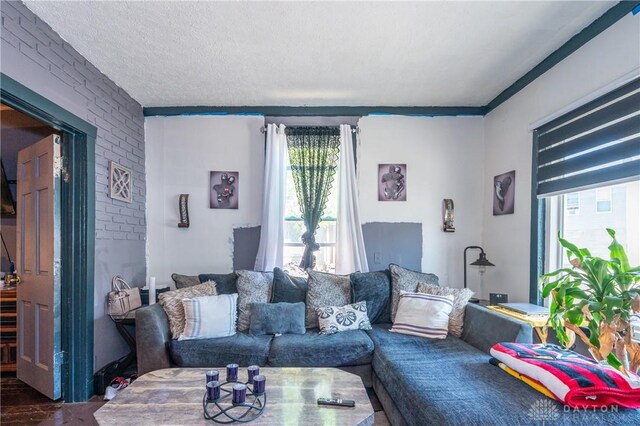 living room featuring a textured ceiling, a healthy amount of sunlight, and brick wall