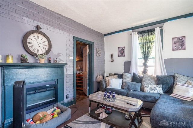 living area featuring a textured ceiling, brick wall, and a glass covered fireplace