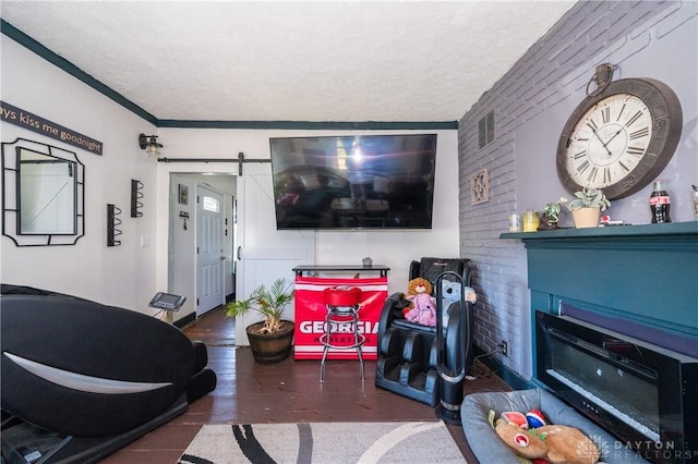 living area with a glass covered fireplace, wood finished floors, a textured ceiling, and a barn door