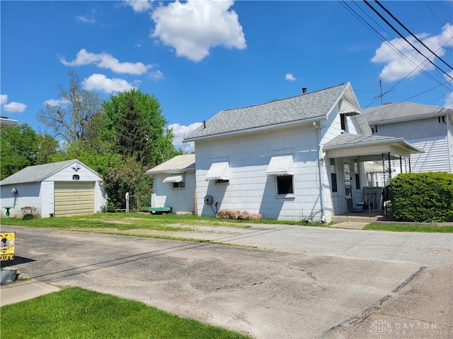 view of property exterior with a garage, an outdoor structure, a porch, and a lawn