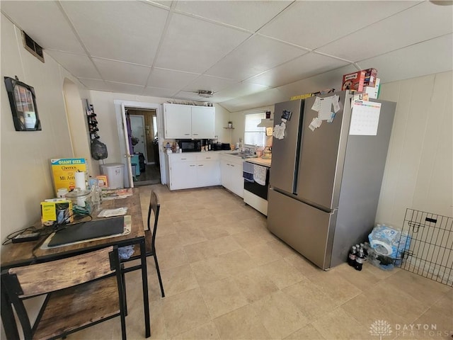 kitchen with sink, a paneled ceiling, stainless steel fridge, dishwasher, and white cabinets