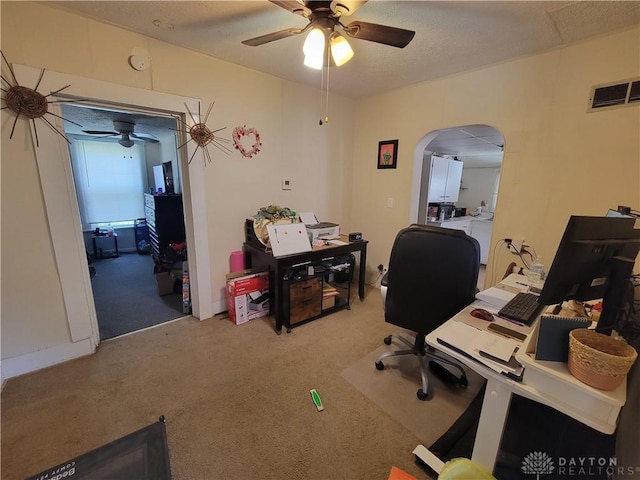 carpeted office with a textured ceiling and ceiling fan