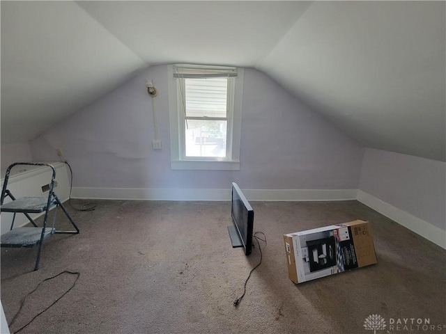 bonus room with dark carpet and vaulted ceiling