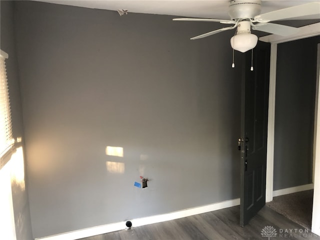 empty room with dark wood-style floors, ceiling fan, and baseboards