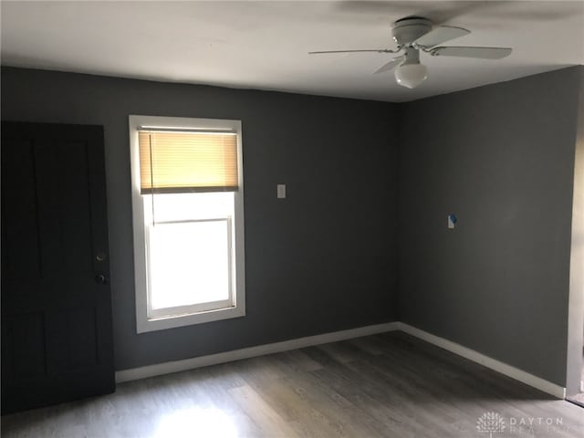 unfurnished room with ceiling fan, wood finished floors, and baseboards