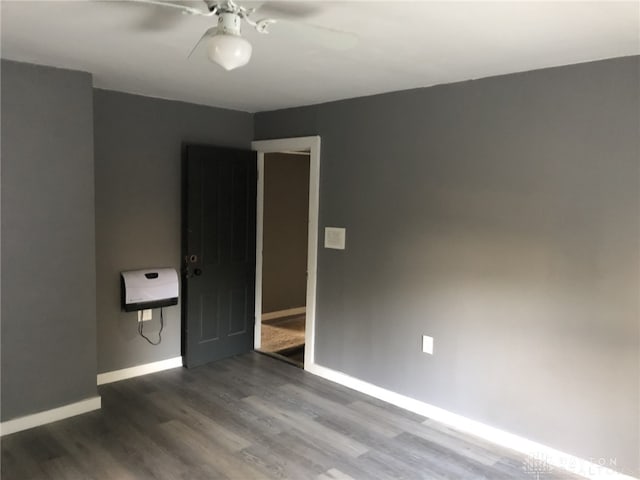 empty room featuring a ceiling fan, baseboards, and wood finished floors