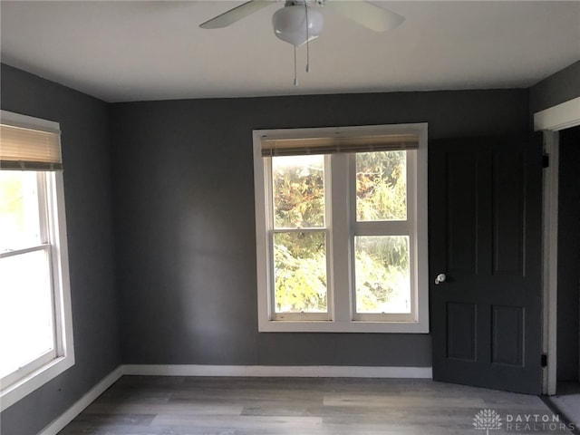 unfurnished room featuring ceiling fan, wood finished floors, and baseboards