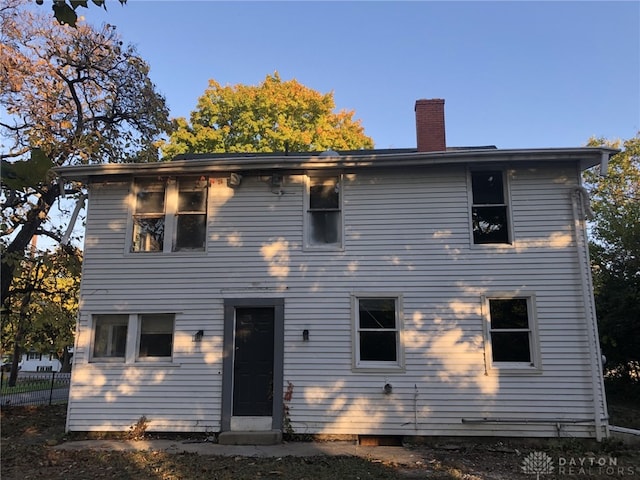 rear view of house featuring fence and a chimney