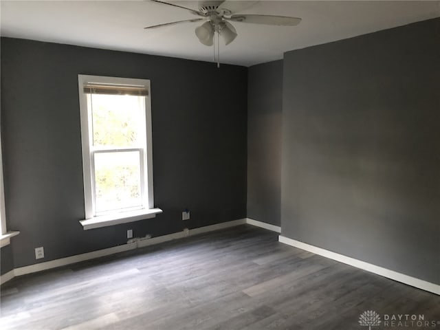 spare room featuring dark wood-style floors, ceiling fan, and baseboards