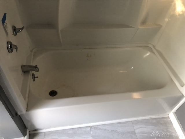 bathroom with a tub to relax in and tile patterned floors