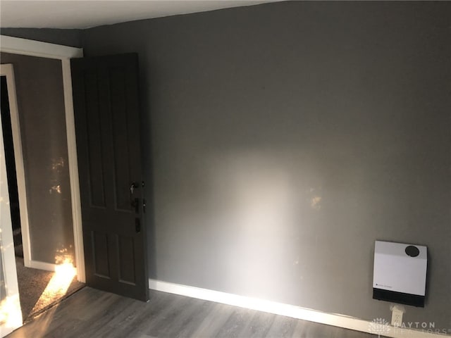 spare room featuring dark wood-style flooring and baseboards