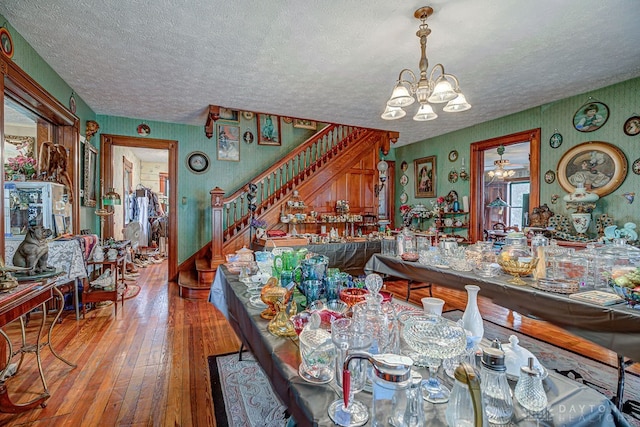 dining room with hardwood / wood-style floors, a notable chandelier, and a textured ceiling