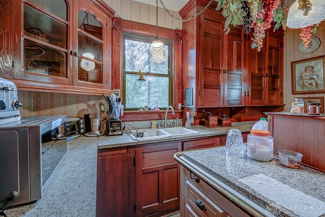 kitchen featuring light stone counters, carpet flooring, sink, and hanging light fixtures