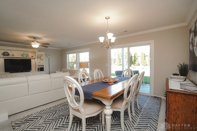 carpeted dining room with ceiling fan with notable chandelier and ornamental molding