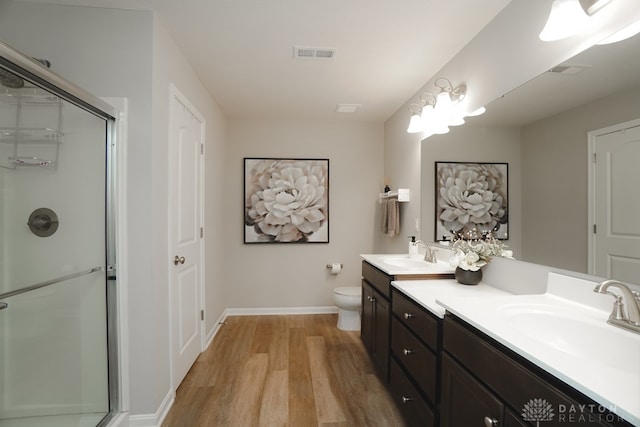 bathroom featuring hardwood / wood-style flooring, vanity, toilet, and a shower with door