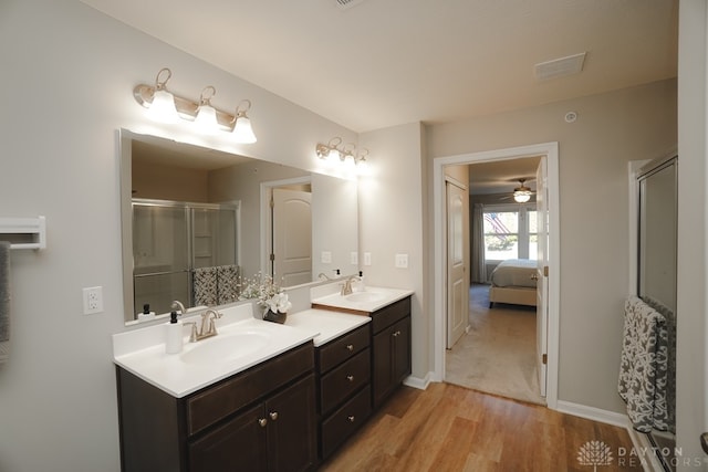 bathroom with hardwood / wood-style floors, vanity, ceiling fan, and an enclosed shower