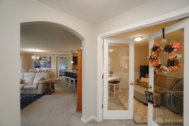 hallway featuring carpet, a chandelier, and a textured ceiling