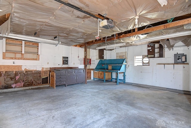 garage featuring a garage door opener, electric panel, and a workshop area