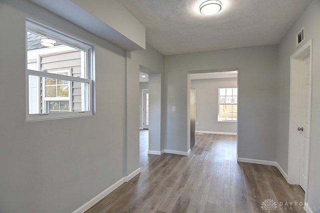 hallway with a textured ceiling and light hardwood / wood-style flooring