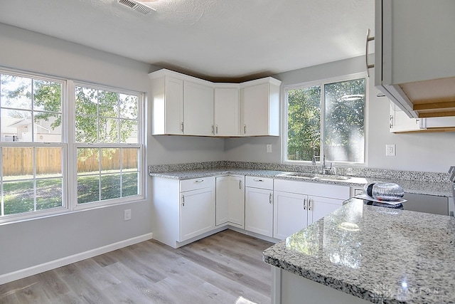 kitchen with light wood-type flooring, plenty of natural light, and white cabinets