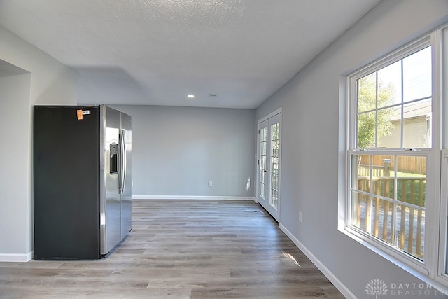 interior space with light wood-type flooring, a textured ceiling, and plenty of natural light