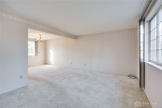 unfurnished room featuring light carpet and an inviting chandelier