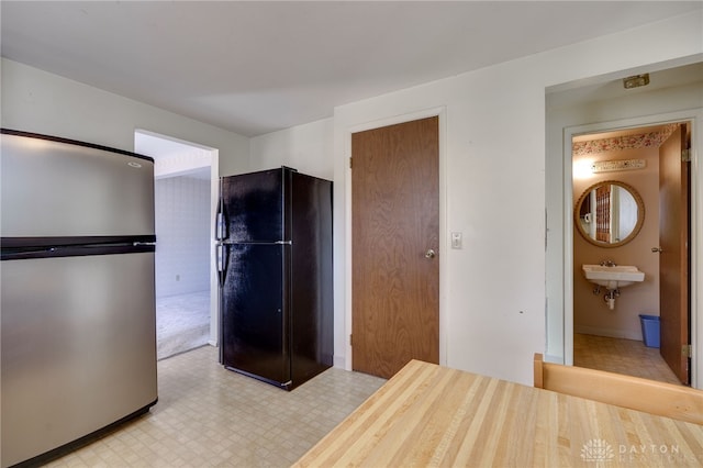 unfurnished bedroom featuring connected bathroom, black refrigerator, and stainless steel refrigerator