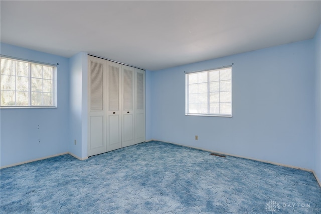 unfurnished bedroom featuring multiple windows, a closet, and carpet