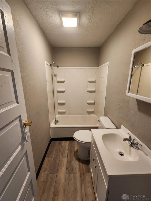 full bathroom with shower / tub combination, toilet, a textured ceiling, and hardwood / wood-style flooring