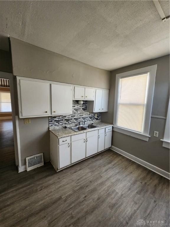 kitchen featuring decorative backsplash, a textured ceiling, sink, white cabinets, and dark hardwood / wood-style floors