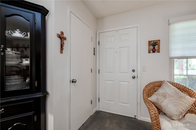 entryway with a textured ceiling and dark carpet