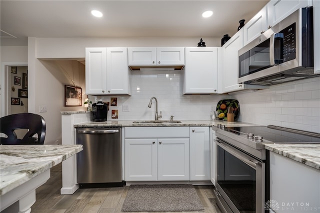 kitchen featuring sink, light hardwood / wood-style floors, stainless steel appliances, white cabinets, and light stone counters