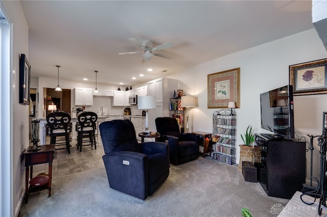 living room with light carpet, sink, and ceiling fan