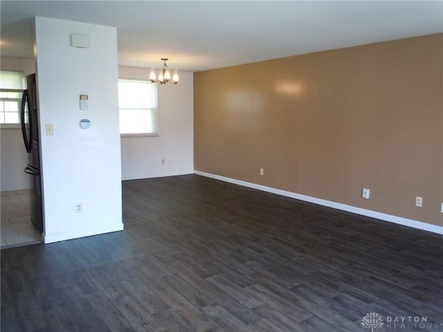 empty room with a chandelier and dark hardwood / wood-style flooring