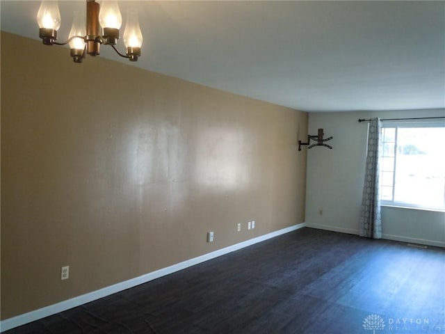 empty room featuring a chandelier and dark wood-type flooring